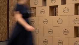 Personne passant devant un mur de cartons avec des dalles de réemploi Eurocoustic