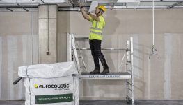 Plafond acoustique Eurocoustic installé dans un atelier de réemploi, avec un opérateur intervenant sur l’ossature technique en hauteur