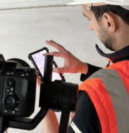 photo d'une personne avec casque de chantier et veste orange fluo avec caméra 