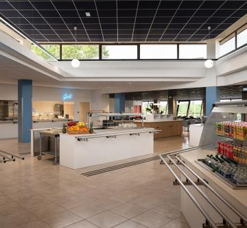 Vue d’ensemble du restaurant d’entreprise Air France avec espaces de restauration lumineux et îlots de service. Un plafond modulaire acoustique Eurocoustic sombre couvre la partie centrale de la pièce, contribuant au confort acoustique et à l’esthétique contemporaine de l’espace.