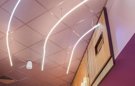 Plafond acoustique coloré avec ossatures assorties et éclairage intégré dans un espace intérieur