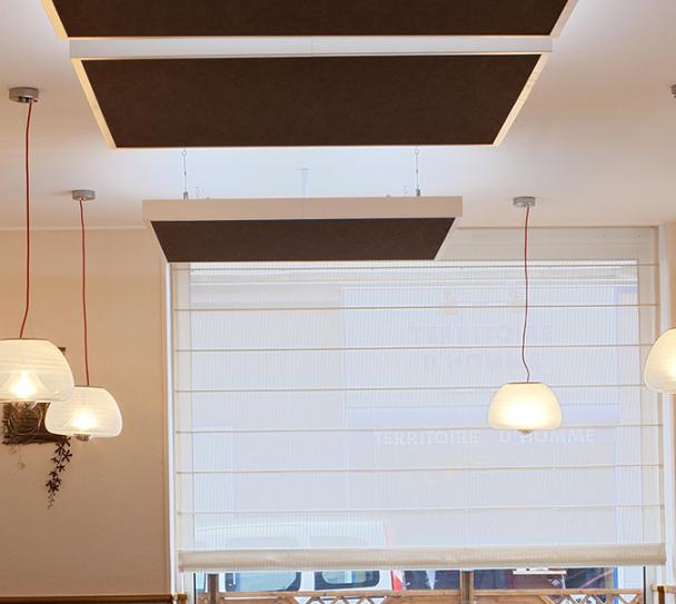 Interior of a modern restaurant featuring acoustic ceiling tiles for improved sound comfort, with warm lighting and contemporary decor.