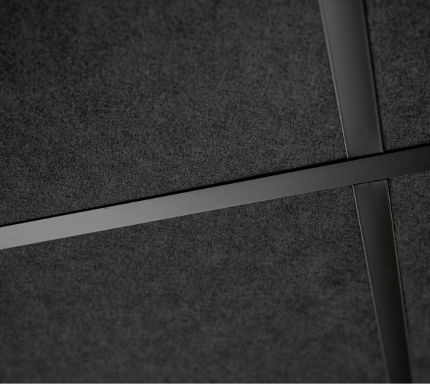 Plafond acoustique modulaire sombre avec ossature apparente en métal, vue en gros plan des dalles et croisillons